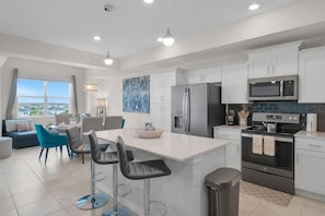 A modern kitchen with white cabinets, stainless steel appliances, and a central island with bar stools. - 3161-401 Resort Lake View Disney Universal Orlando (Kissimmee)
