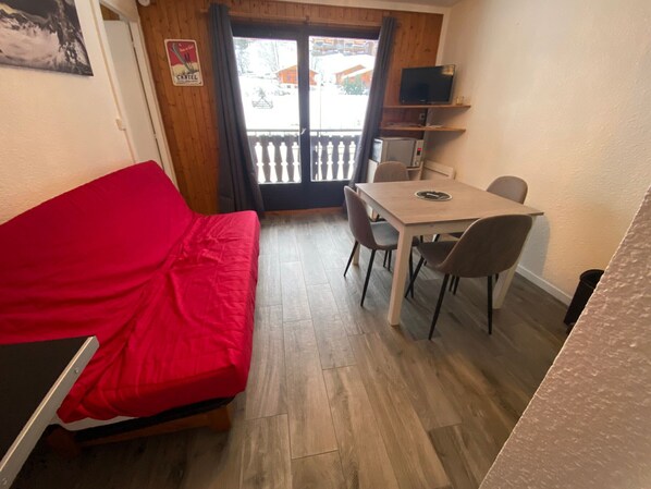 Cozy living space with a sofa, dining area, and balcony access.