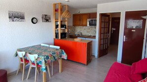 A compact living space with a dining area, kitchen, and a red sofa.
