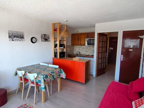 Ein kompakter Wohnraum mit Essbereich, Küche und einem roten Sofa.