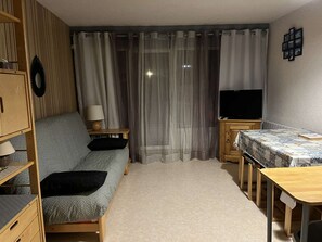 A compact living space with a sofa, a television, a small table, and a cabinet. - Studio cabin for 4 at the foot of the slopes with balcony and parking - Auris en Oisans (Auris)