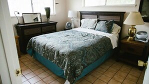 Una camera da letto con un letto, un comodino, una cassettiera, una scrivania e una finestra.