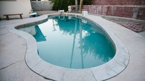 Una piscina con bordo curvo e solarium piastrellato.