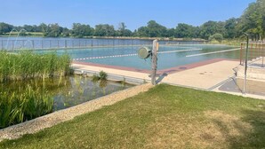 A swimming pool with lane dividers, a grassy area, and a body of water.