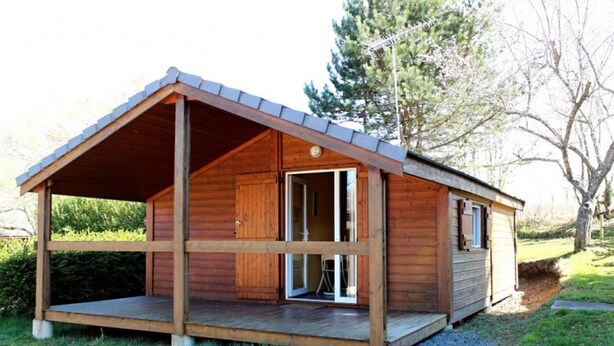 A wooden cabin with a covered porch and a large sliding glass door.