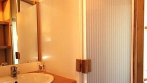 A bathroom with a wooden vanity, a white sink, and a mirror.