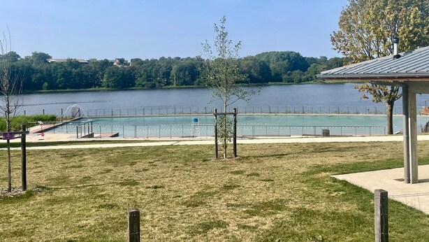 A lakeside park with a swimming pool, a covered pavilion, and a grassy area.