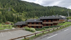 A lodge with a parking lot, surrounded by forested hills. - Cozy studio near slopes with private parking (Châtel)