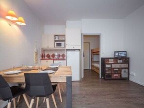 Uma cozinha compacta com micro-ondas, geladeira e um pequeno espaço de refeições com mesa e cadeiras.
