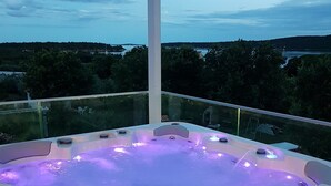 Un jacuzzi con vistas a un lago y colinas al fondo.