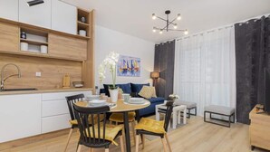 A modern kitchen with white cabinets, a wooden countertop, and a dining area with a round table and chairs.