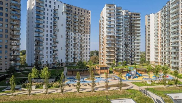 A residential area with high-rise apartment buildings, a playground, and landscaped areas.
