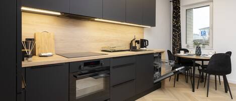 Una cocina moderna con armarios negros, encimera de madera y horno empotrado.