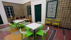 Une pièce avec un sol carrelé, des chaises vertes et blanches, une table blanche et une porte verte.