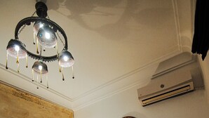 Une pièce avec un mur recouvert de carreaux à motifs, une cheminée en briques, un miroir rond et un lustre.