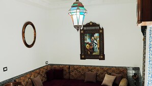 Un salon avec un grand canapé, une table basse en bois, un tapis à motifs, une lanterne suspendue et un tableau encadré au mur.