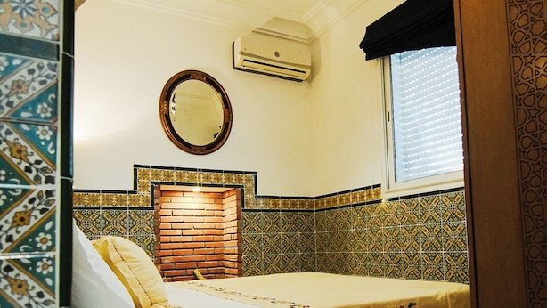 Une chambre avec un lit, un miroir et un lustre.