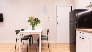 A modern kitchen with a white refrigerator, wooden countertop, and a dining area with a white table and black chairs. - Casa Moderna - Two Bedroom Apartment (Corfu)