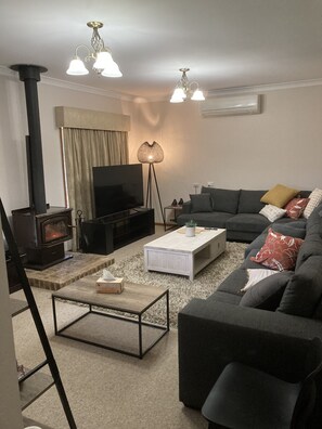 Ein Wohnzimmer mit Kamin, einer Couch, einem Couchtisch und einem Fernseher.