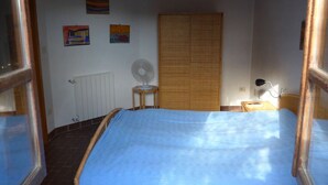 Une chambre à coucher avec un lit, un radiateur, un ventilateur et une armoire.