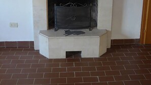 Une cheminée ornée d’une silhouette de chat, un tableau au-dessus, et une plante en pot sur la droite.