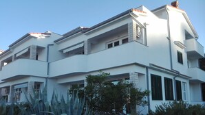 A modern two-story building with balconies, large windows, and a well-maintained garden with agave plants.