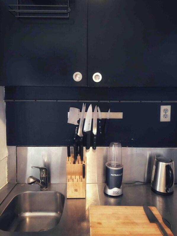 Kitchen equipped with a stainless steel sink, knife block, blender, and kettle.