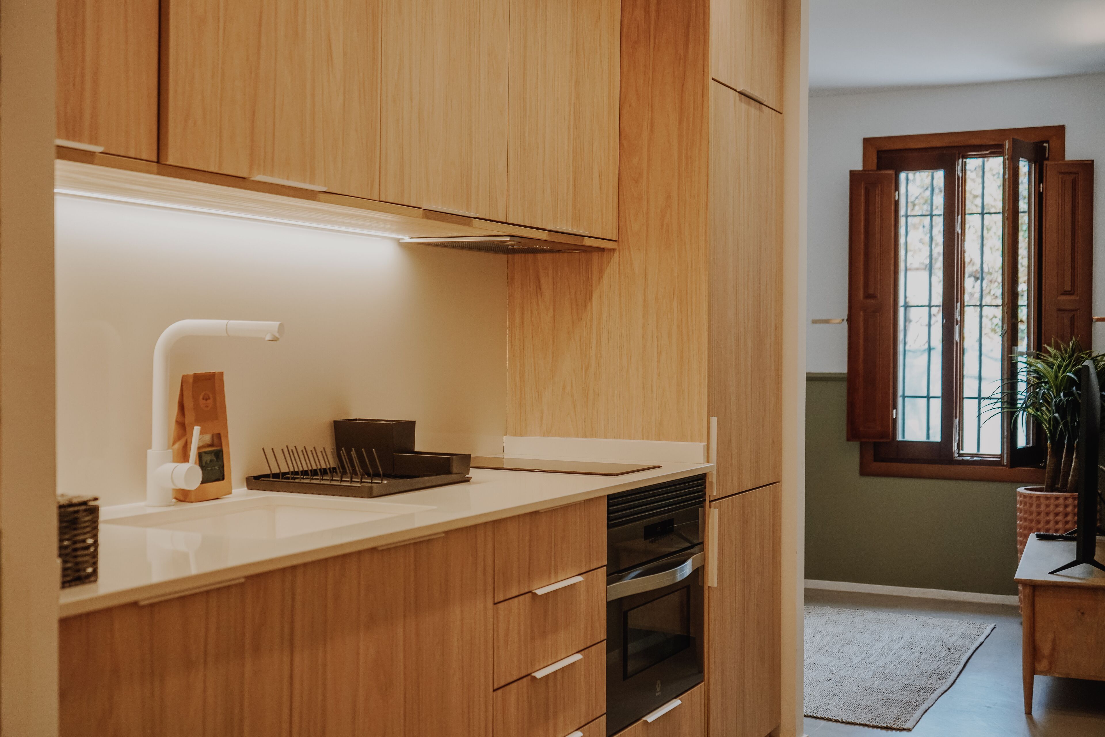 A modern kitchen with wooden cabinets, a white countertop, and a built-in oven.
