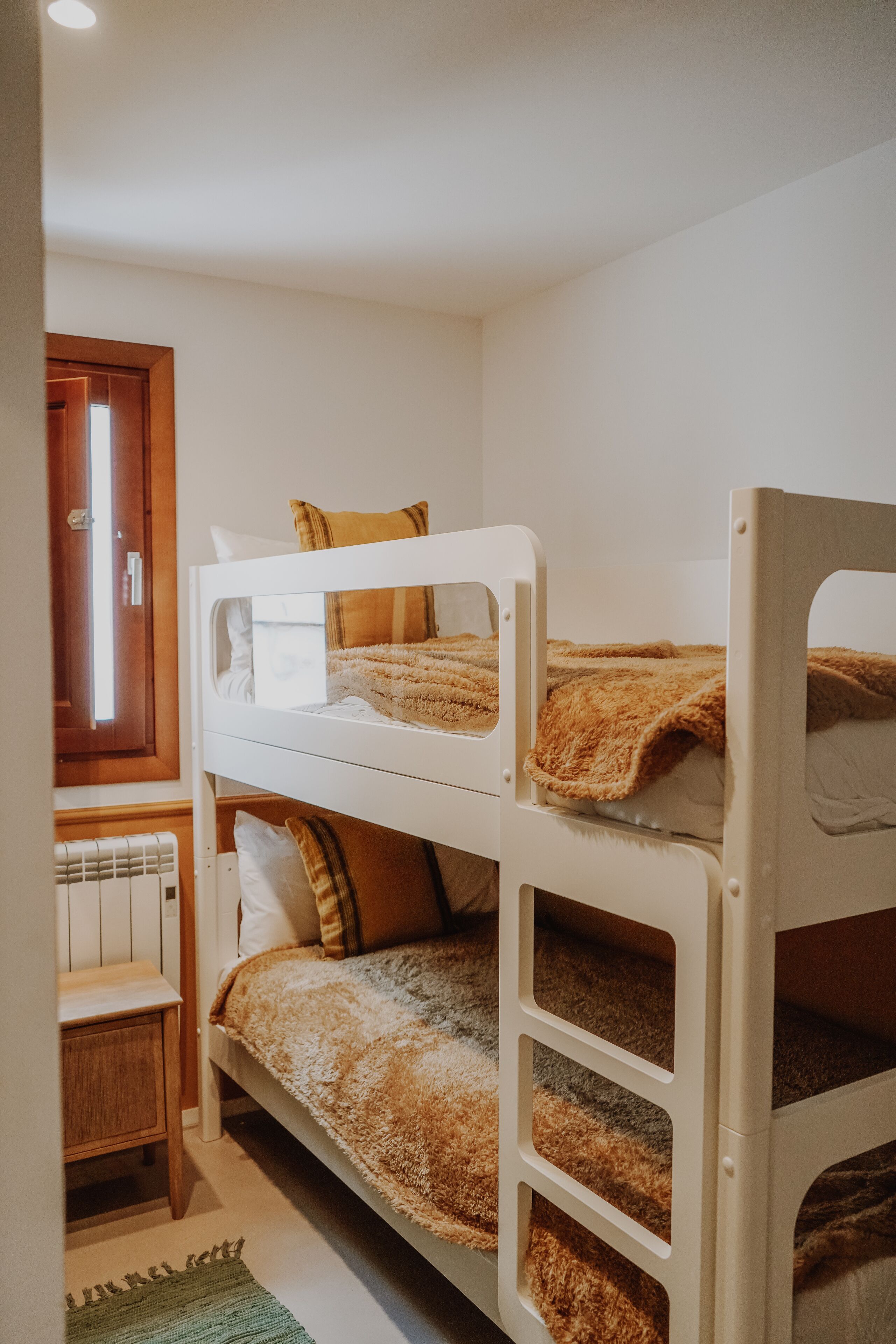 Una camera con un letto a castello, una porta in legno, un comodino e un tappeto verde.