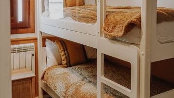 Una camera con un letto a castello, una porta in legno, un comodino e un tappeto verde.