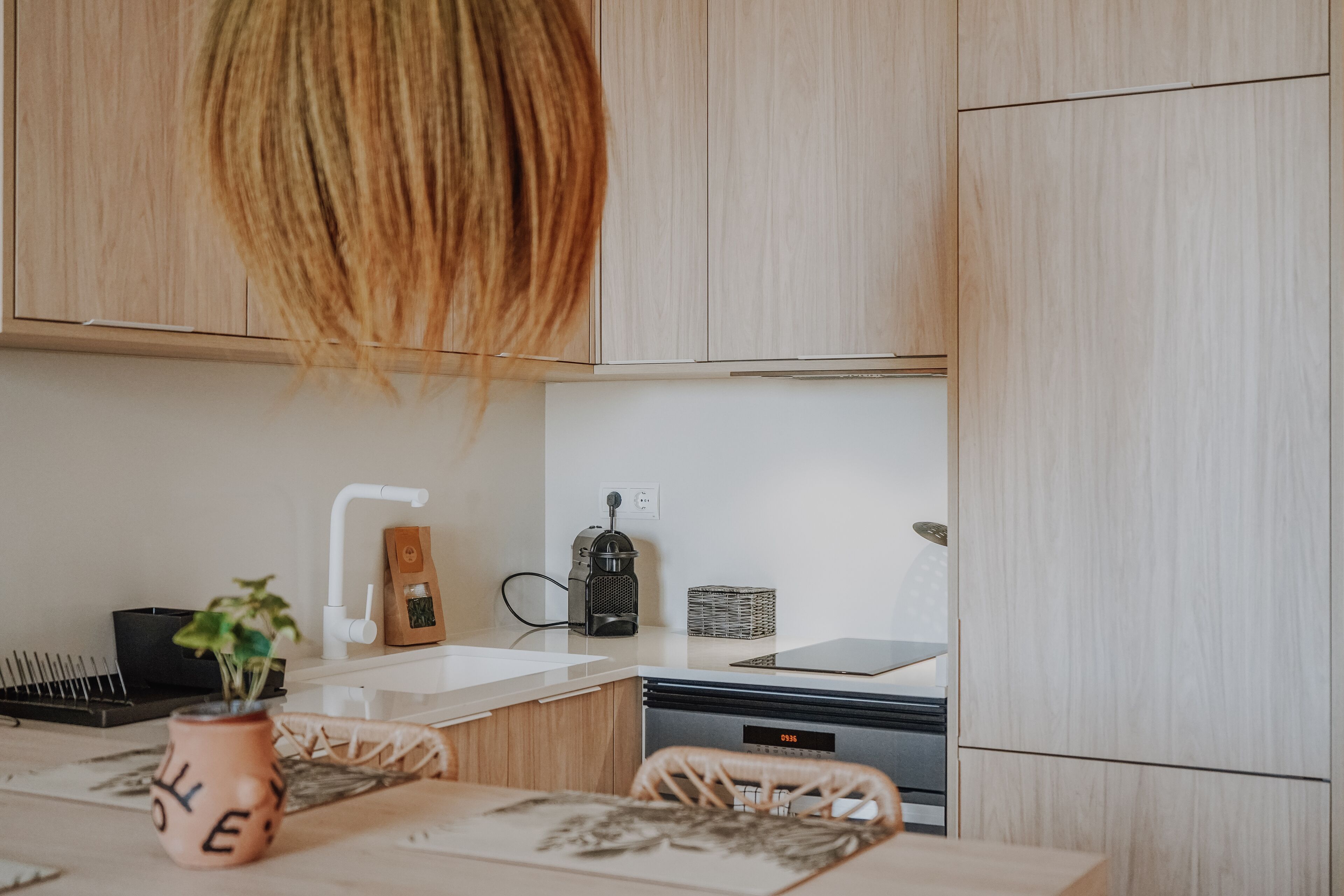 A modern kitchen with wooden cabinets, a coffee maker, a tablet, and a dishwasher.