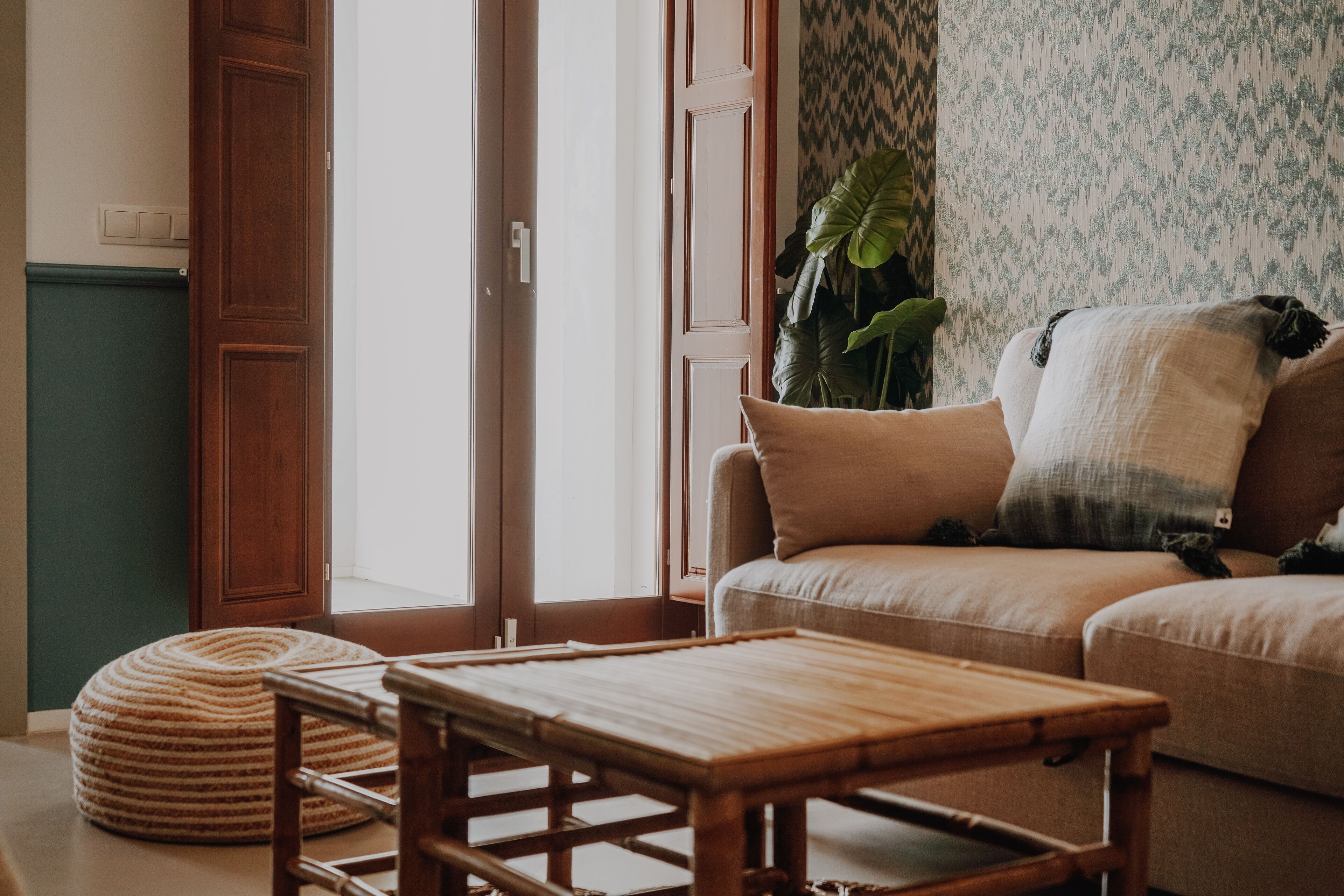 Un salon avec un canapé, une table basse en bois et un pouf rond.