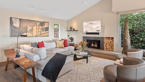 A modern living room with a fireplace, a sofa, a coffee table, and a bookshelf. - Stunning Panoramic Views From Contemporary Riviera Home! (Santa Barbara)