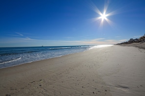A beach with a clear sky and the sun shining.