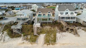 Una proprietà fronte mare con diverse case, tra cui una grande con un balcone e una più piccola con un portico.