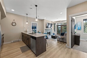A modern kitchen with a central island, built-in dishwasher, and pendant lighting.