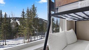 Una cama litera con vista a una montaña nevada y árboles.
