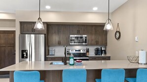 Una cocina moderna con electrodomésticos de acero inoxidable, armarios de madera y taburetes de bar azules.