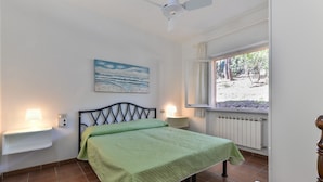 A bedroom with a bed, a ceiling fan, a window with a view, and bedside lamps. - Holiday Apartment 'Il Papavero' with Wi-Fi (procchio)