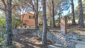 A stone wall, trees, and a building with a balcony. - Holiday Apartment 'Il Papavero' with Wi-Fi (procchio)