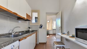 A compact kitchen with white cabinets, a built-in oven, a dishwasher, and a window above the sink. - Holiday Apartment 'Il Papavero' with Wi-Fi (procchio)