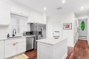 A modern kitchen with white cabinetry, stainless steel appliances, and a central island. - Magnolia By The Sea, Heated Community Pool, 3 Bikes, 4 Minute Walk to Private Beach - BeachWalk (Panama City Beach)