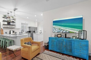 A modern kitchen with white cabinets, a central island, and a dining area with green stools.