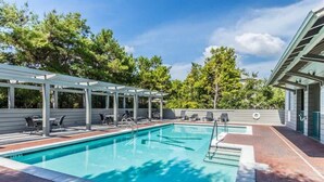A swimming pool with a covered area, lounge chairs, and a brick pathway. - Magnolia By The Sea, Heated Community Pool, 3 Bikes, 4 Minute Walk to Private Beach - BeachWalk (Panama City Beach)