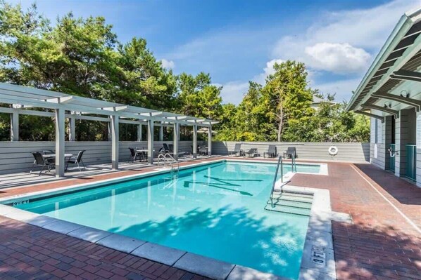 A swimming pool with a covered area, lounge chairs, and a brick pathway. - Seacrest West - BeachWalk (Panama City Beach)