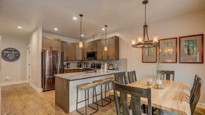 Una cocina moderna con electrodomésticos de acero inoxidable, armarios de madera e iluminación colgante.