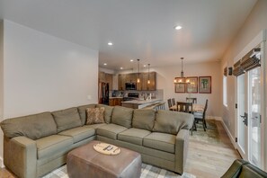 A modern living room with a sectional sofa, a coffee table, and a dining area with a table and chairs. - Blue Bear Lodge - Prime location - Air Conditioning - WiFi - Fireplace (McCall)