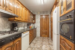 Une cuisine avec des meubles de rangement en bois, une cuisinière, un lave-vaisselle et un réfrigérateur.