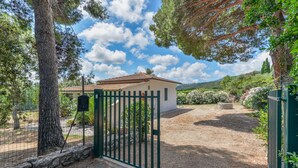 A gated property with a white building, a stone wall, and a clear sky.