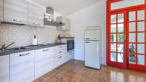 A kitchen with white cabinets, a stainless steel sink, a built-in oven, and a white refrigerator.